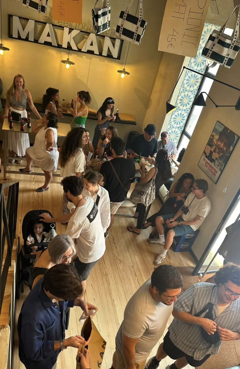 Interior de Makan lleno de gente bajo el letrero MAKAN